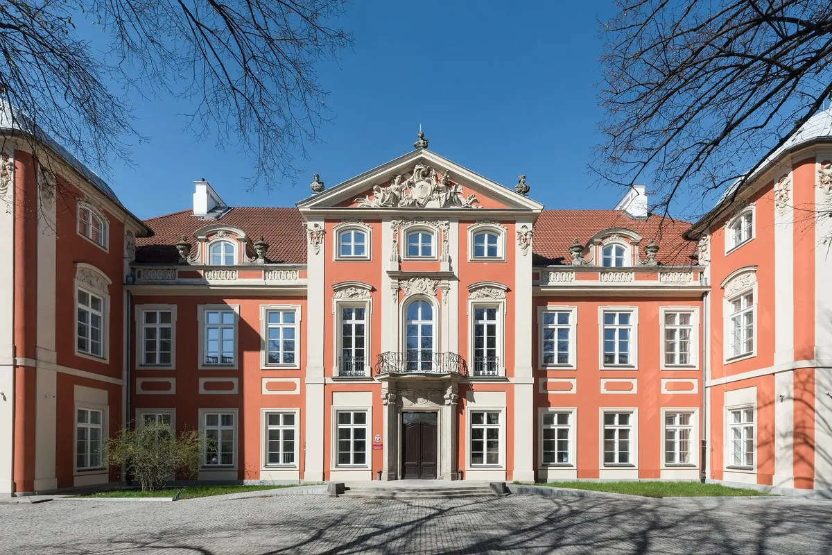 The pink and white Baroque front of the Czapski Palace in Warsaw seen across a courtyard on a clear day